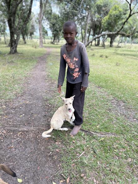 Young boy with white dog on path, Kenya