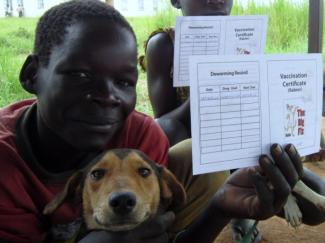 boy smiling with dog and holding up vaccination certificate