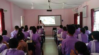 "Image showing a group of PCL 1st-year nursing students attentively listening to a presentation on rabies and its prevention. The presenter,Mr Anup Muni Bajracharya, Microbiologists, explains the transmission, symptoms, and preventive measures of rabies, including vaccination and proper wound care. Educational posters or slides about rabies displayed in the background."