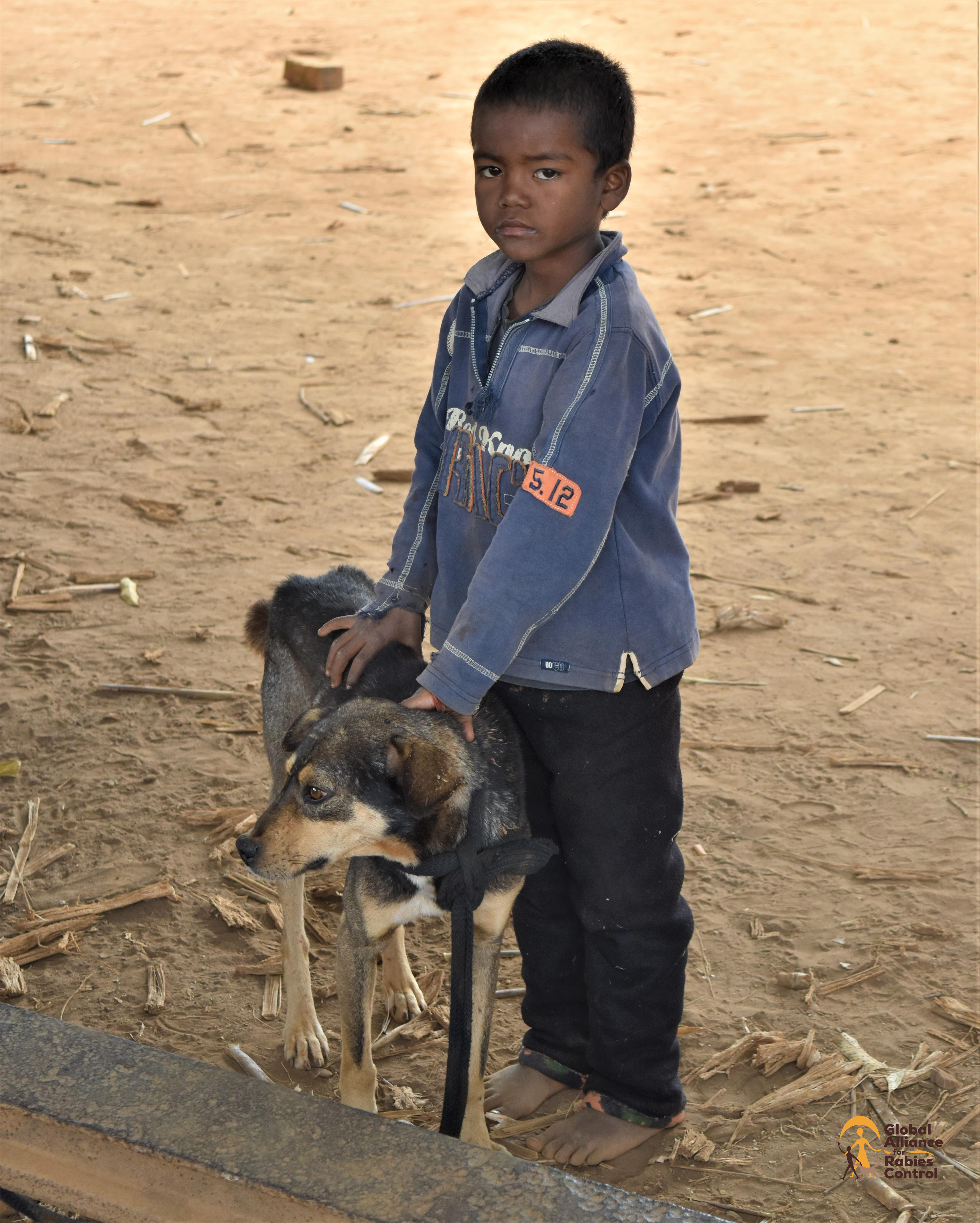 A little boy stands with his dog waiting for it to be vaccinated against rabies. GARC, Madagascar